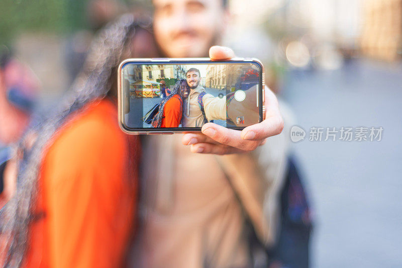 multiracial young couple taking a selfie with smartphone – happy multicultural couple taking photo